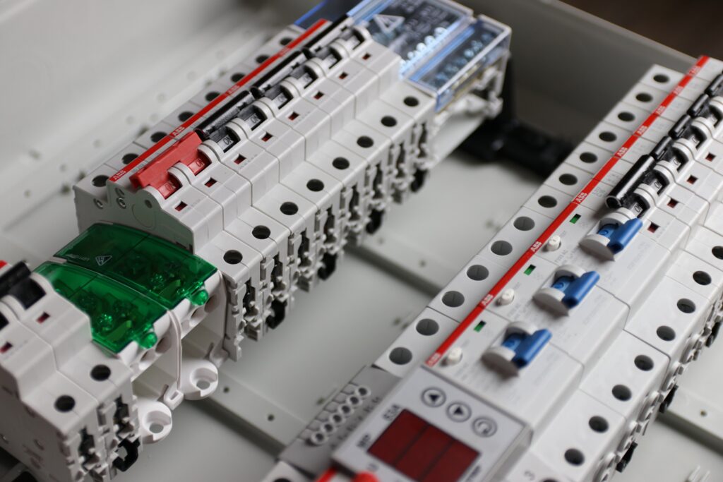 Specjalista wykonujący precyzyjne pomiary instalacji elektrycznej za pomocą nowoczesnych narzędzi pomiarowych. Zdjęcie ilustruje naszą dbałość o bezpieczeństwo, zgodność z normami oraz najwyższą dokładność w usługach elektrycznych i automatyce przemysłowej.